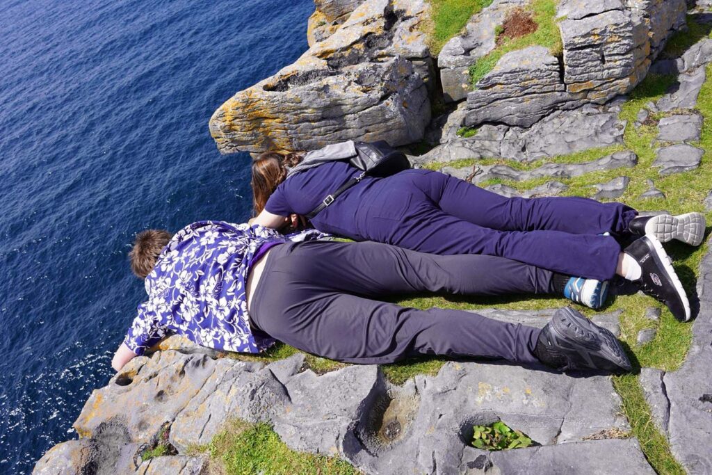 Couple wearing purple clothes lying at the edge of a cliff