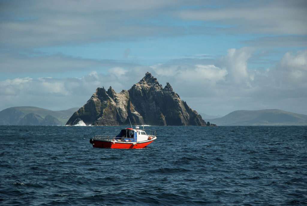 View of Skellig Island behind a red boat.